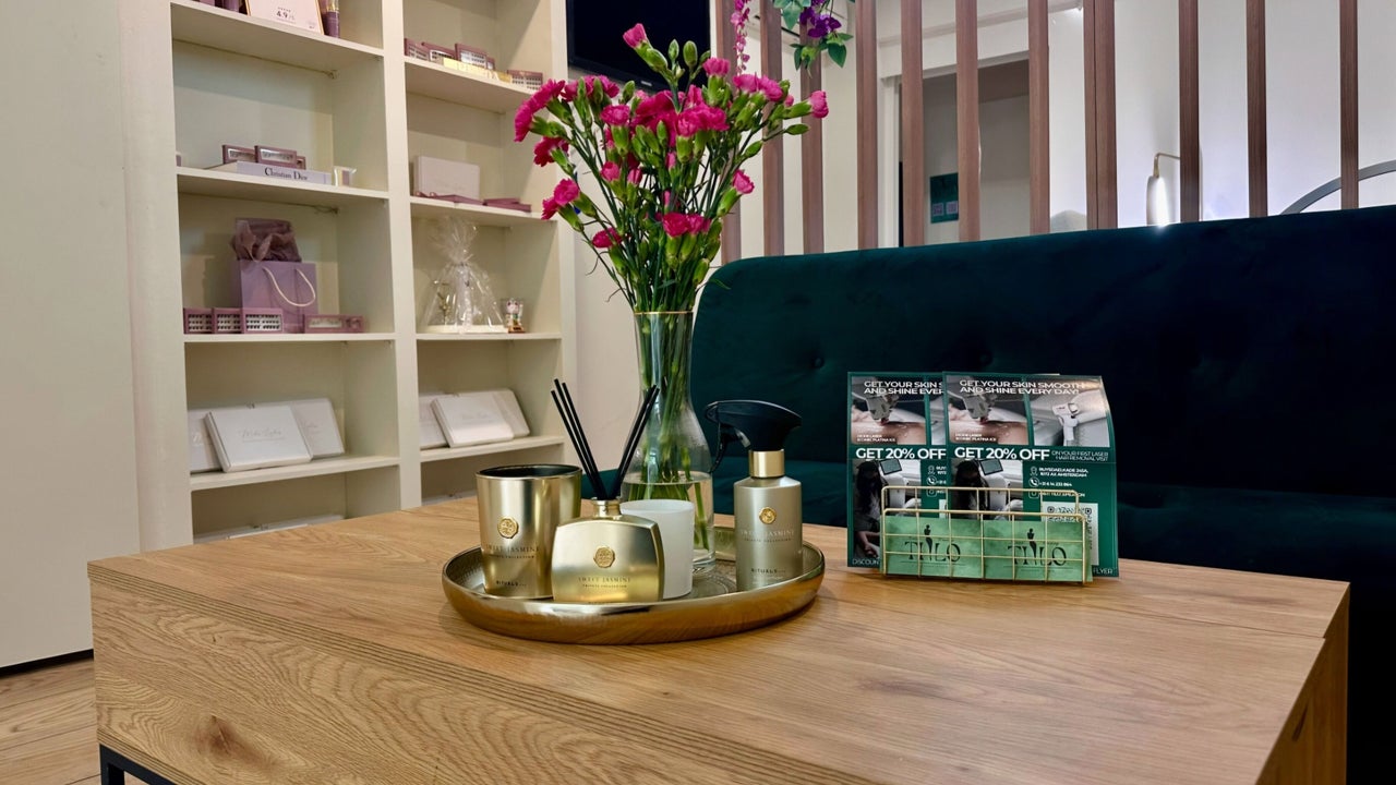 De zithoek met een houten tafel, bloemen op een gouden dienblad en een groene bank
