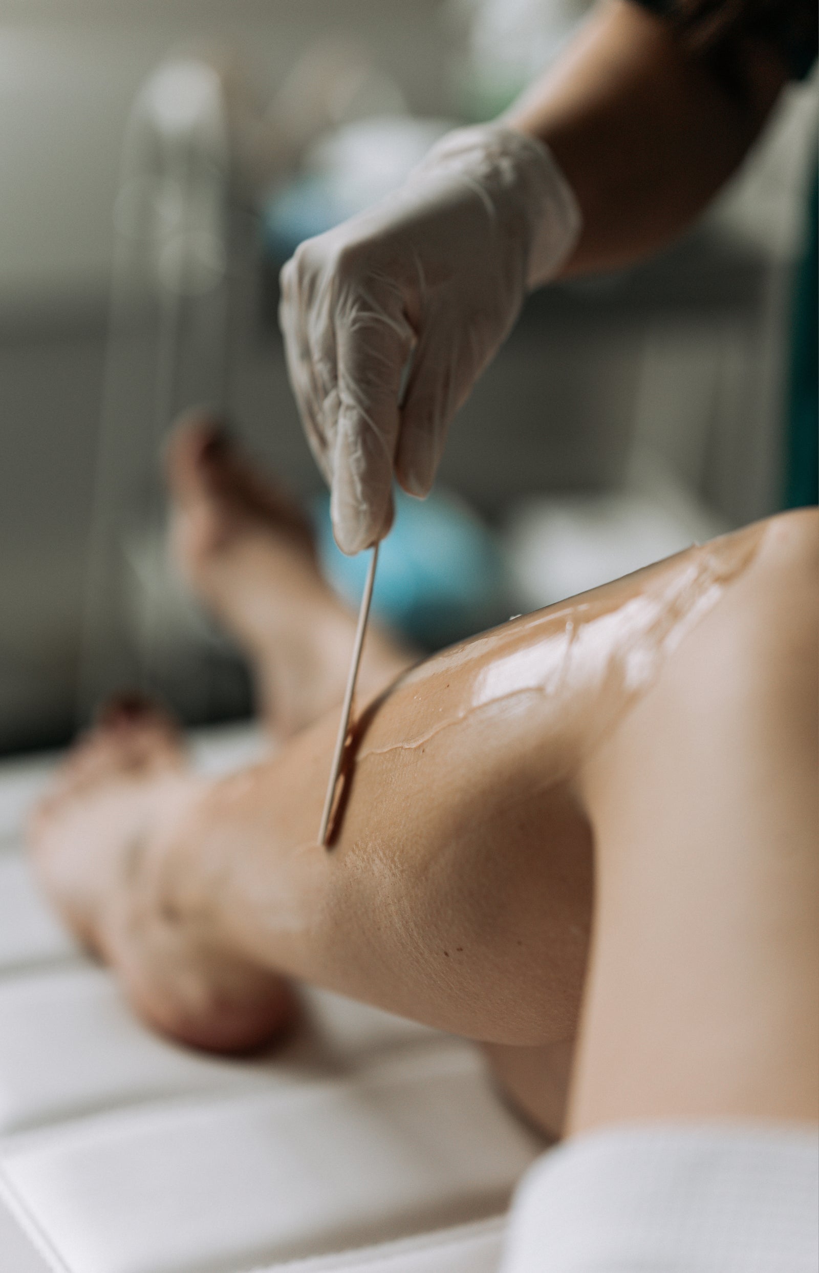 Een gehandschoende hand brengt met een spatel wax aan op een been